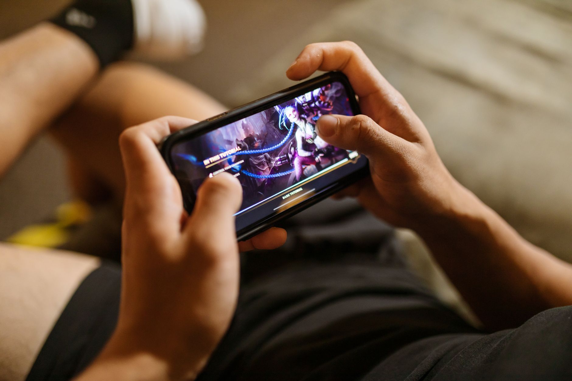 Une personne joue à un jeu vidéo mobile sur un smartphone, se concentrant sur le style de vie du jeu et de la technologie.