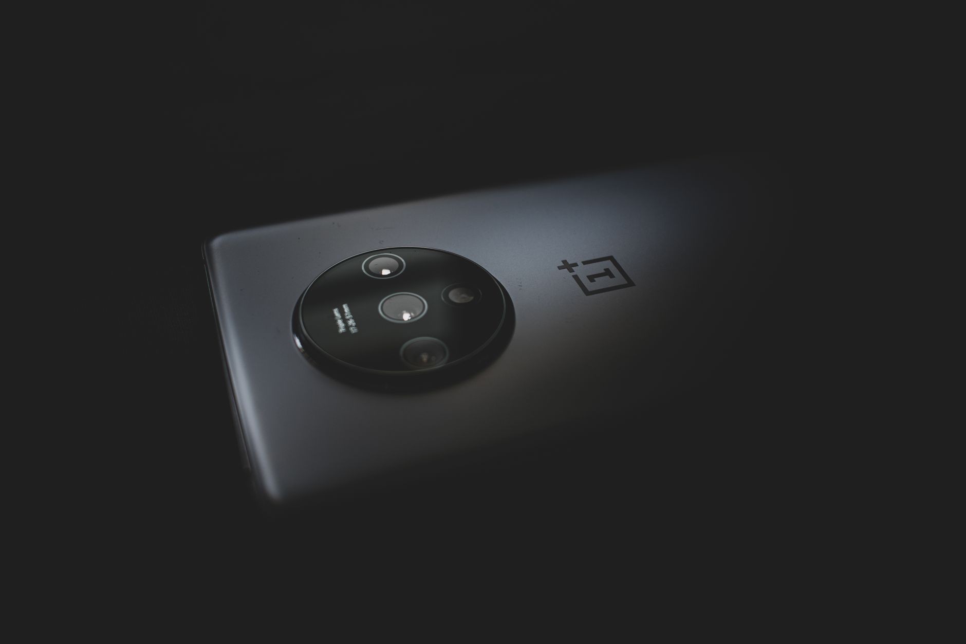 Dos d’un smartphone moderne avec un bloc photo circulaire, éclairé dans l’obscurité.